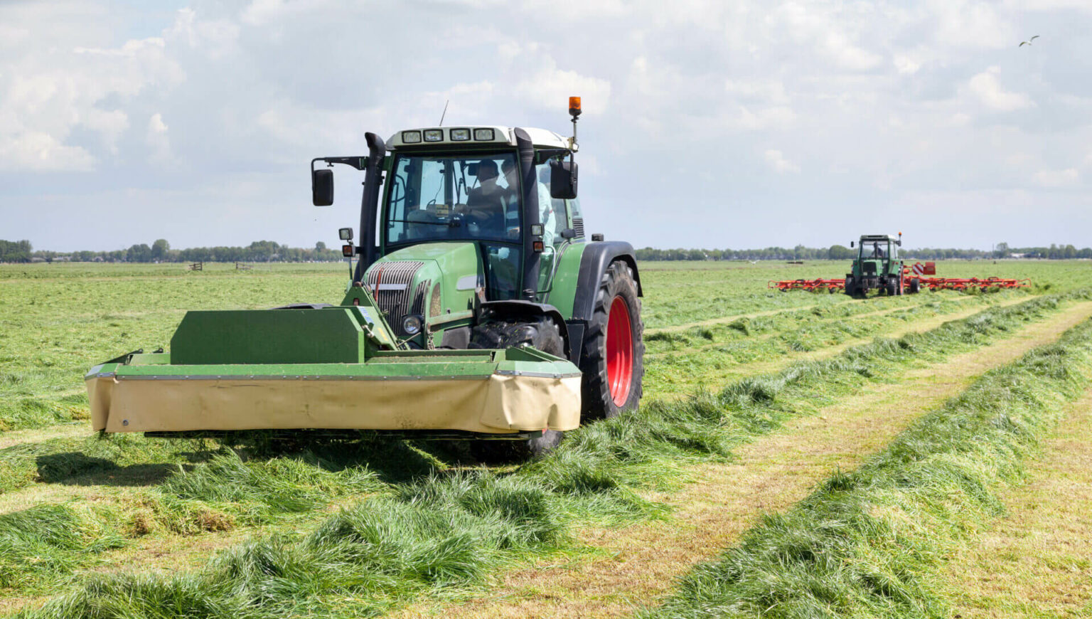 tractor and mower in green meadow in the netherlands